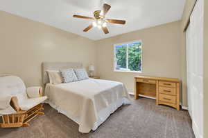 Bedroom featuring a closet, light colored carpet, baseboards, and ceiling fan