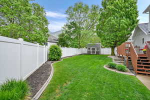View of yard featuring a wooden deck, a shed, an outdoor structure, and stairway