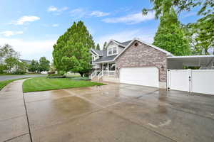 View of front of home with brick siding, concrete driveway, a garage, a gate, and a porch