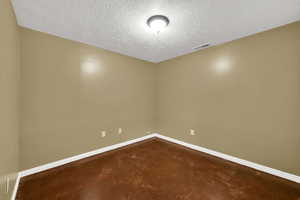 Spare room featuring concrete floors, a textured ceiling, and baseboards