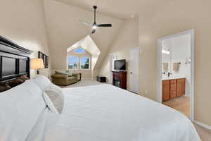 Bedroom with vaulted ceiling, light carpet, baseboards, connected bathroom, and a sink