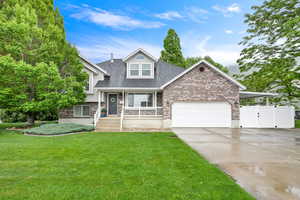 Split level home featuring covered porch, brick siding, a garage, driveway, and roof with shingles