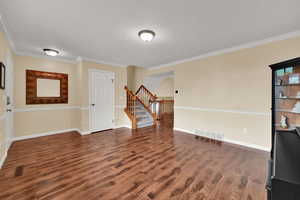 Spare room with stairs, wood finished floors, ornamental molding, baseboards, and a textured ceiling