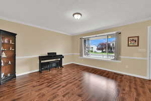 Spare room with wood finished floors, ornamental molding, baseboards, and a textured ceiling