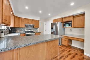 Kitchen with stainless steel appliances, under cabinet range hood, a sink, light wood-style floors, and recessed lighting