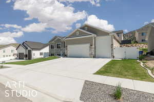 View of front of house featuring a gate, an attached garage, stone siding, driveway, and a residential view