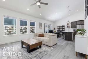 Living room with lofted ceiling, a ceiling fan, light wood-style flooring, recessed lighting, and baseboards