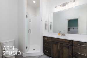 Bathroom featuring a stall shower, vanity, toilet, and wood finished floors