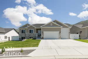Craftsman house with a gate, stone siding, an attached garage, and concrete driveway