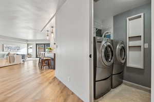 Laundry room with separate washer and dryer, light wood finished floors, and baseboards