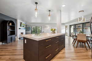Kitchen with light wood-style floors, decorative light fixtures, dark brown cabinetry, and modern cabinets
