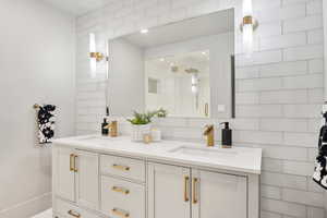 Bathroom featuring backsplash, a shower stall, and double vanity