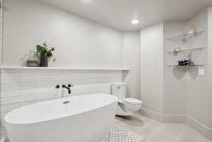 Bathroom featuring toilet, a soaking tub, recessed lighting