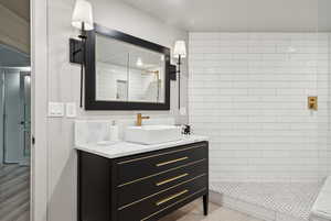 Full bath with tiled shower and vanity