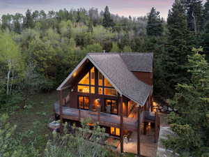 Back of house at dusk featuring a shingled roof