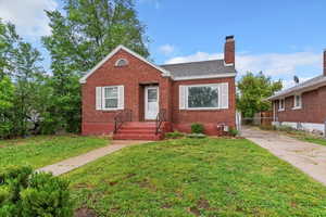 Bungalow featuring brick siding and roof with shingles