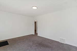 Front room with arched walkways, carpet, and baseboards