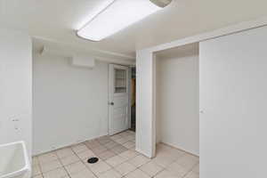 Laundry room with a closet, light tile patterned floors, and baseboards