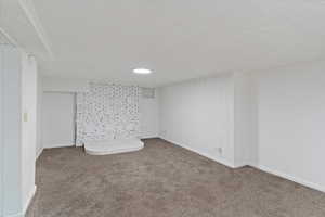 Finished basement family room featuring carpet floors, a textured ceiling, and baseboards