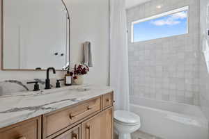 Bathroom featuring toilet, vanity, and shower / bath combination with curtain