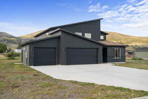 View of front of home with a mountain view, concrete driveway, a garage, and board and batten siding