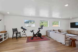 Exercise area with light wood finished floors and recessed lighting
