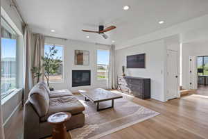 Living room featuring ceiling fan, light wood-style floors, baseboards, a glass covered fireplace, and recessed lighting
