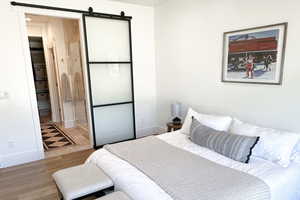 Bedroom with wood finished floors, baseboards, and a barn door