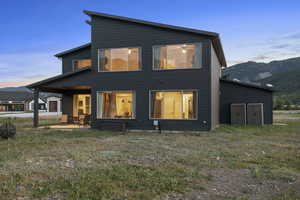 Back of house at dusk with a patio area, a mountain view, and a fire pit