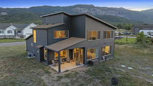 Back of house with a patio, a mountain view, and roof with shingles