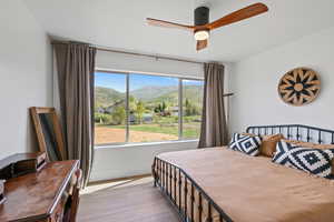 Bedroom with a mountain view, wood finished floors, a ceiling fan, and baseboards