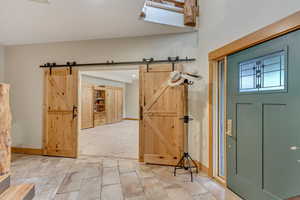 Foyer entrance featuring a barn door, baseboards, and light carpet