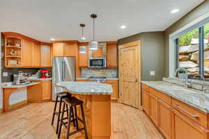 Kitchen with appliances with stainless steel finishes, a sink, light wood finished floors, backsplash, and recessed lighting