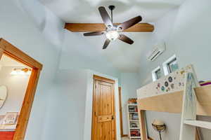 Bedroom featuring a wall unit AC, lofted ceiling, and a ceiling fan