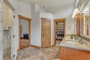 Full bath featuring a stall shower, double vanity, and a closet