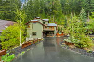 View of front of property with a chimney, a wooded view, asphalt driveway, and metal roof