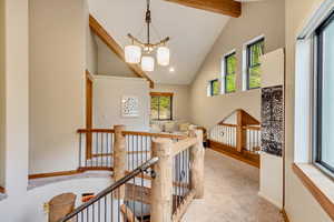 Hallway with high vaulted ceiling, beamed ceiling, plenty of natural light, and an upstairs landing