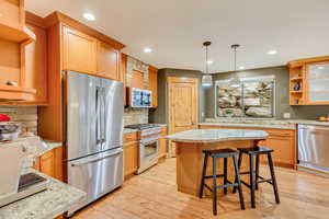 Kitchen with appliances with stainless steel finishes, decorative backsplash, a sink, light wood-type flooring, and recessed lighting