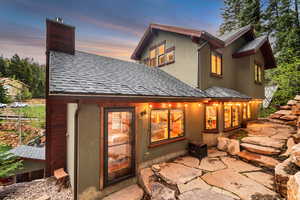 Rear view of property with a shingled roof, a chimney, and a patio