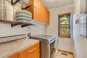 Laundry area with cabinet space, washer and clothes dryer, and baseboards