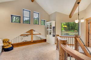 Hall with carpet floors, an upstairs landing, beamed ceiling, and high vaulted ceiling