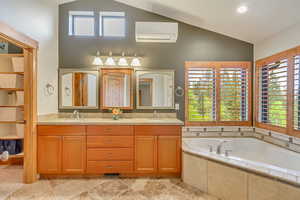 Bathroom featuring high vaulted ceiling, a wall unit AC, healthy amount of natural light, and a bath