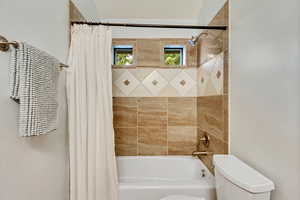 Bathroom featuring shower / bathtub combination with curtain and toilet