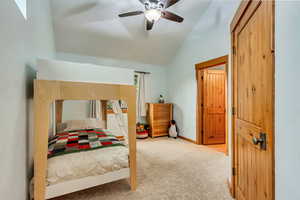 Carpeted bedroom featuring lofted ceiling, a ceiling fan, and baseboards