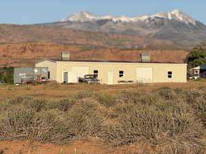 Back of house featuring a mountain view, an outbuilding, a pole building, and a garage