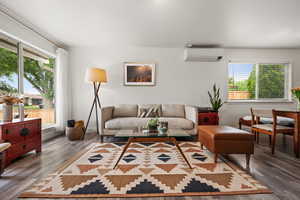 Living area featuring an AC wall unit and wood finished floors