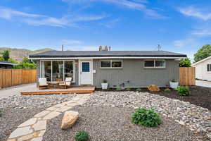 View of front of house with a wooden deck, fence, brick siding, and roof with shingles