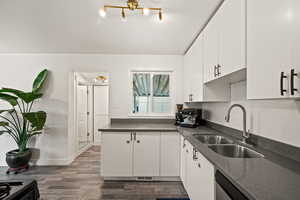 Kitchen featuring a sink, white cabinetry, dark wood-style flooring, and gas range
