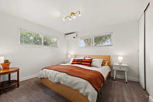 Carpeted bedroom featuring an AC wall unit and baseboards