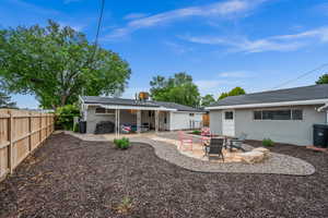 Rear view of property featuring a fire pit, a patio area, a fenced backyard, and brick siding
